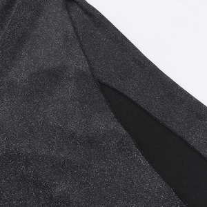 Detailed close-up of glittering metallic fabric with side slit on a black evening gown