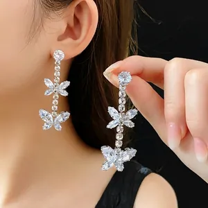 Silver butterfly tassel earrings with sparkling cubic zirconia on a dark background