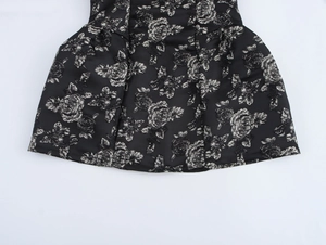 Close-up of black floral jacquard fabric with rose pattern and shiny texture on the dress