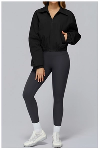 Full-body shot of a cropped black zip-up sports jacket and high-waisted gray yoga pants