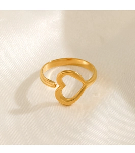 Close-up of golden hollow heart-shaped open ring on a luxury beige silk background