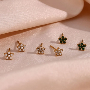 Détail de boucles d'oreilles fleur avec perles, zircons et émeraudes sur soie