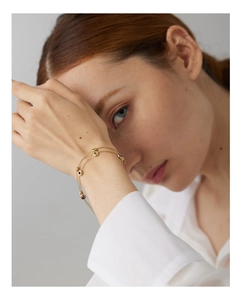Detail of double-layer gold necklace with colorful round gemstones worn by a model