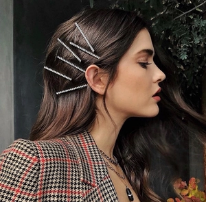 Détail de cinq barrettes à cheveux en strass étincelants portées sur le côté des cheveux
