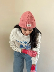 Detalle de guantes de punto de rayas rojas y blancas con gorro rosa y sudadera gris