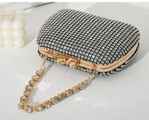Detailed macro view of a luxury sparkling rhinestone clutch bag with gold chain and handle