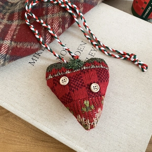 Detail of red knitted heart ornament with wood buttons on a decorative book