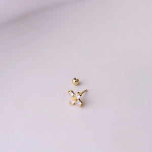 Minimalistischer goldener Titanstahl-Ohrstecker mit Zirkonia-Kreuz auf rosa Hintergrund