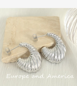 Detailed macro shot of silver spiral textured earrings on a white silk background