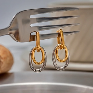 Boucles d'oreilles classiques bicolores en U entrelacées sur fond de fourchette inox