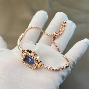 Detail of rose gold square watch with blue dial and sparkling rhinestones on the band