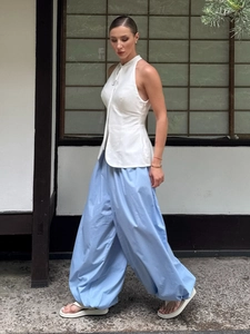 Outdoor view of lightweight sky blue harem pants and a white halter top set in motion