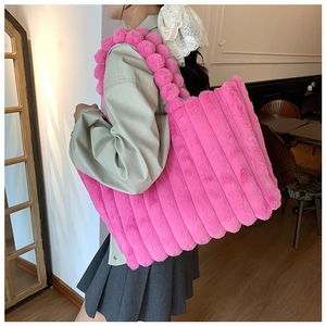 Detailed macro of bright pink plush tote bag with striped texture and bubble ball handle