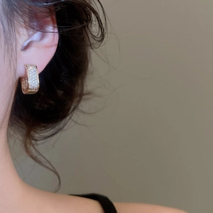 Close-up of elegant gold C-shaped hoop earrings with sparkling pave-set cubic zirconia