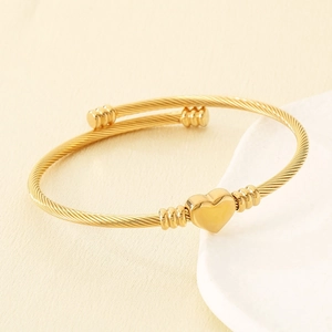 Détail d'un charme coeur doré sur un bracelet câble torsadé avec finition polie