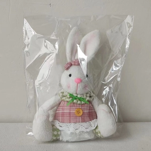 Detail of Easter bunny plush toy in pink plaid dress with green bow and lace trim