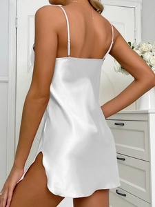 Détail d'une nuisette blanche en satin avec fines bretelles et ourlet fendu sur le côté