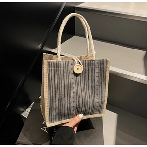 Detail of striped linen tote bag featuring vertical patterns and button closure detail