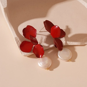 Detailed close-up of red floral earrings with white baroque pearls on a stone tray