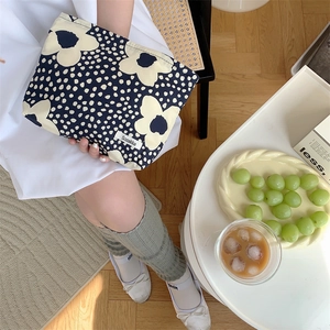 Close-up of a floral cotton makeup bag with navy blue fabric and cream flower patterns