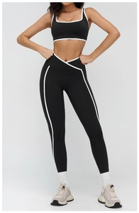 Close-up of black yoga set featuring white piping and V-shape cross waistband detail
