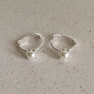 Detail of silver pearl drop hoop earrings with minimalist metal finish and vintage style