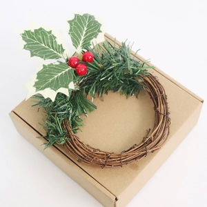 Gros plan d'une mini couronne de Noël artificielle avec baies rouges en boîte carton