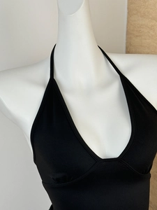 Close-up of black halter neck top with deep V-neckline and slim fit tailoring
