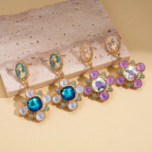 Vintage bohemian cameo earrings with floral crystal drops and gold finish on stone background