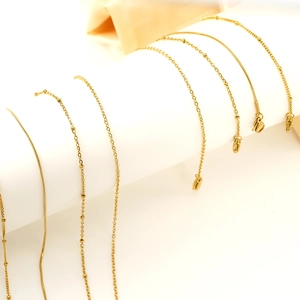 Selection of 18K gold-plated stainless steel snake and bead chains on white displays