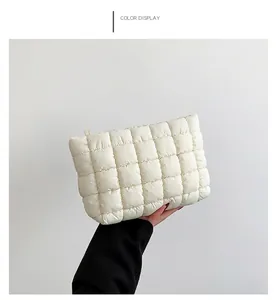 Detailed side view of white quilted padded makeup bag with gold metal zipper closure