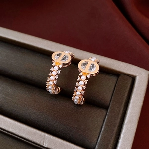 Macro shot of 18k gold plated C-shaped earrings with pearls on dark velvet background