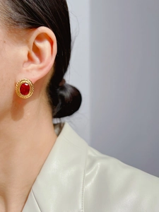 Detail of vintage red oval gemstone earrings with a gold textured bezel on a model