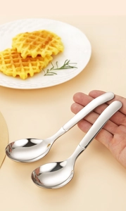 Close-up of thick stainless steel dessert spoon held over a waffle and ceramic plate