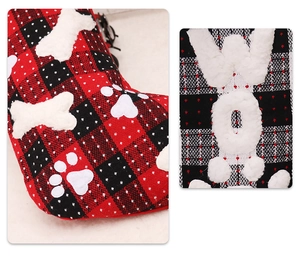 Detail of red and black buffalo plaid Christmas stocking with white plush bone and paw
