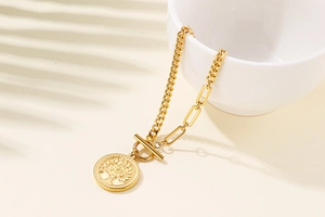Détail du collier doré avec pendentif arbre de vie et fermoir en T sur une chaîne mixte