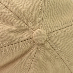 Detailed macro view of khaki newsboy hat top with herringbone texture and central button