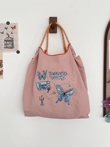 Detail of pink canvas tote featuring blue butterfly embroidery and colorful woven handles