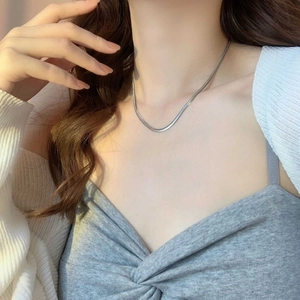 Close-up of a sleek silver titanium steel herringbone flat snake chain on a model neck