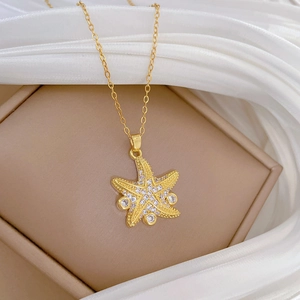 Elegant gold starfish pendant necklace with crystal zircons on a white silk background