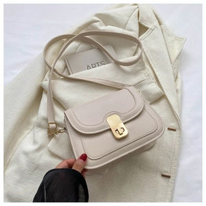 Detail of elegant beige leather crossbody bag with premium gold rotating lock and flap