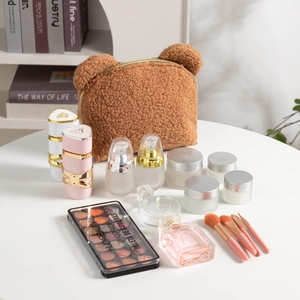 Teddy plush teddy bear makeup bag with cute ears and a gold zipper on a white table