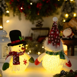 Detail of plush glowing Christmas snowman and elf figures with warm LED light decor