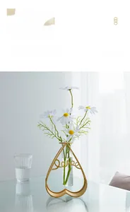 Detail of a gold heart-shaped love metal stand with a glass vase and white daisies