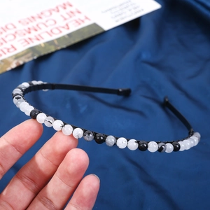 Close-up of 6mm natural crystal stone beads with marble texture on black headband