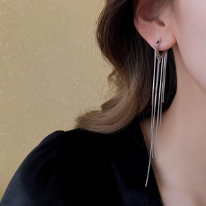 Gros plan de longues boucles d'oreilles à pompons argentés portées par un mannequin chic