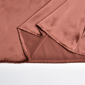 Gros plan de la couture de l'ourlet d'une robe en satin rouge brique au fini soyeux