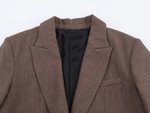 Gros plan détaillé du revers du blazer marron et de la texture fine du tissu sur blanc