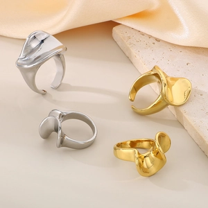 Detail of 18K gold and silver wavy irregular rings on stone base with beige silk cloth
