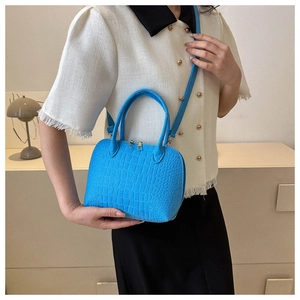 Detail of bright blue faux crocodile leather handbag with elegant gold hardware accents